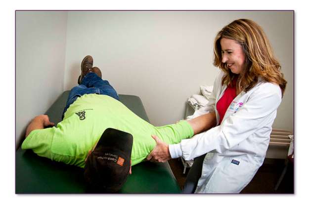 Linda Stanley, assisting a patient, with a shoulder issue.